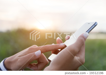 hand using phone outdoor at sunset 19312196