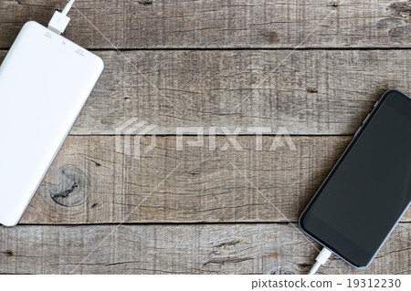 phone charging with power bank on wood background 19312230