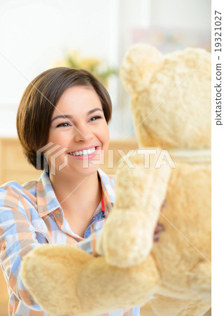 Teenage girl playing with teddy bear.  19321027