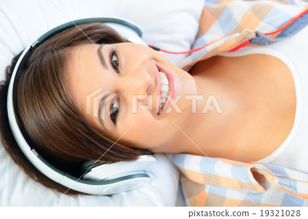Teenage girl lying in bed and listening to music. 19321028