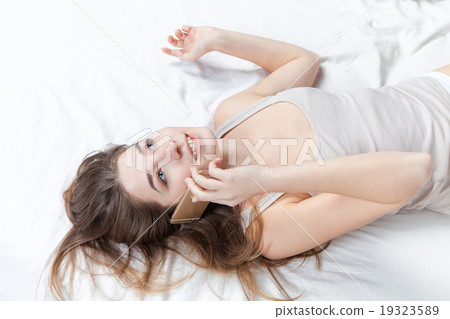 The young girl in bed with phone The young girl in bed with phone 19323589