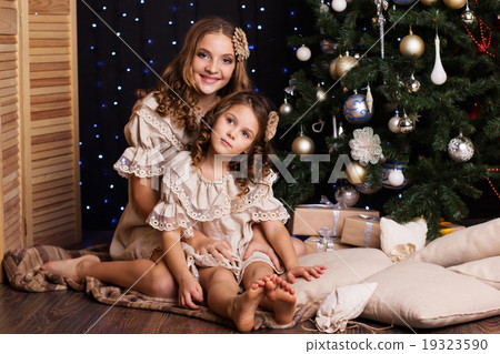 Two sisters with gifts near christmas tree Two sisters with gifts near christmas tree 19323590