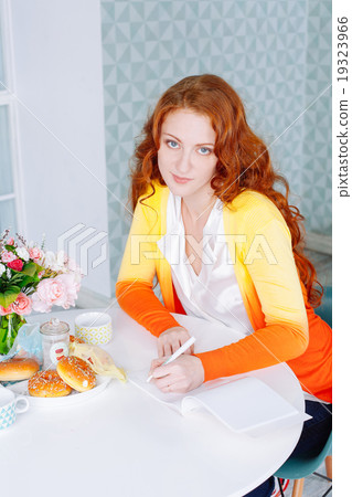 Beautiful woman in her kitchen writing on a notebook  at home 19323966