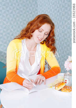 Beautiful woman in her kitchen writing on a notebook at home Beautiful woman in her kitchen writing on a notebook at home 19323968