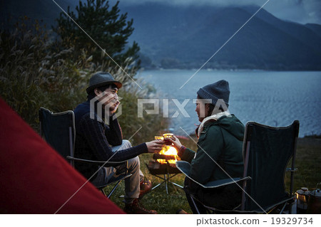 A couple making a toast in front of a bonfire A couple making a toast in front of a bonfire 19329734