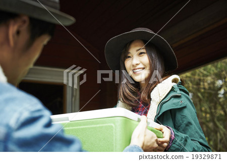 一個男人把一個冷藏箱遞給一個女人 19329871