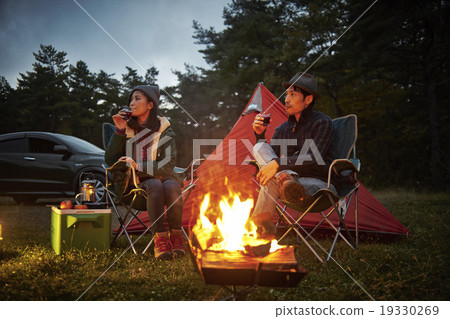 Couple drinking wine by the campfire Couple drinking wine by the campfire 19330269