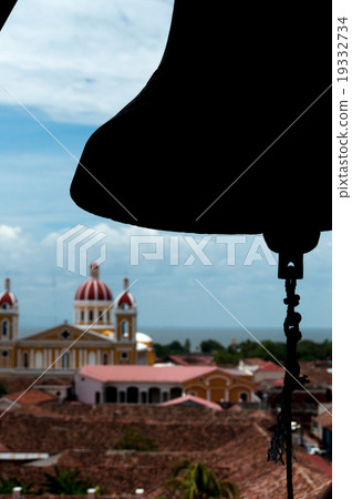 Silhouette of a bell over chuch and house rooftops 19332734