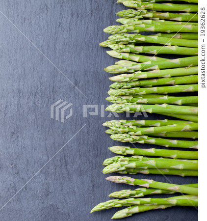 Asparagus sprouts on a black stone background. 19362628
