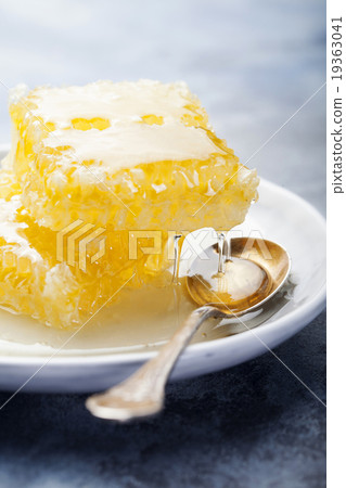 Honeycomb with flowing honey on a plate and spoon 19363041
