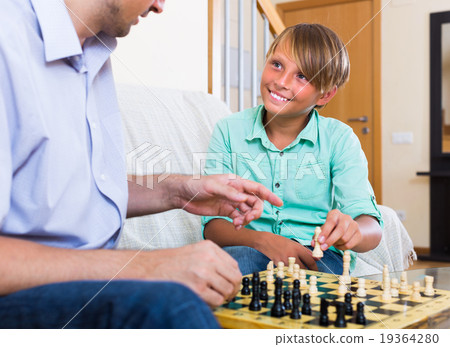 Man and teenager son playing chess. 19364280