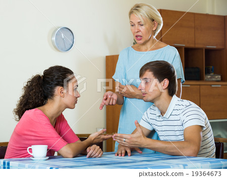 Upset female retiree watching adult kids quarrelling at home 19364673