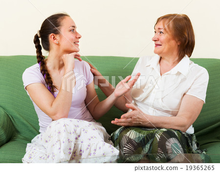 Mature mother and adult daughter gossiping 19365265