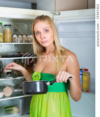 Woman holding foul food near fridge Woman holding foul food near fridge 19365462