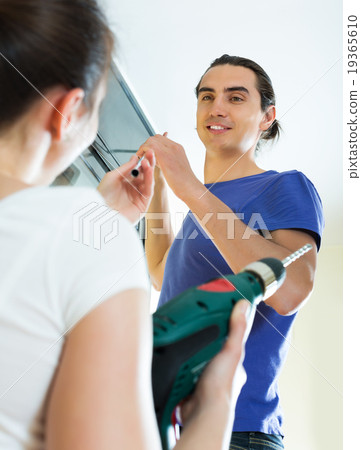 Couple hanging curtains at window 19365610