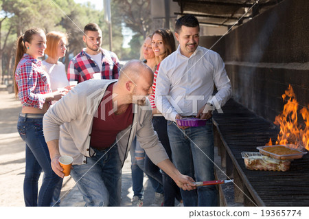 Colleagues making grill at picnic 19365774