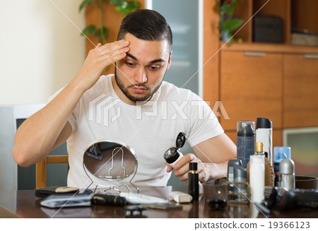 man applying facial cream at home 19366123