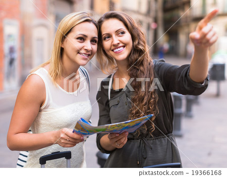 Two women with baggage checking route outdoors 19366168