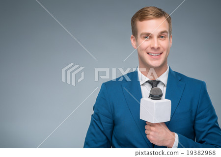 Smiling newsman holding a microphone.  19382968