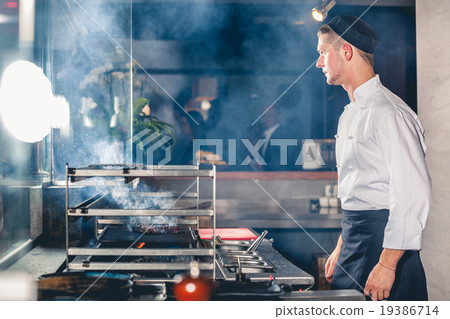 male cook preparing meal on grill 19386714