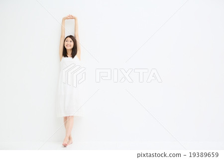 A woman leaning against a white wall 19389659