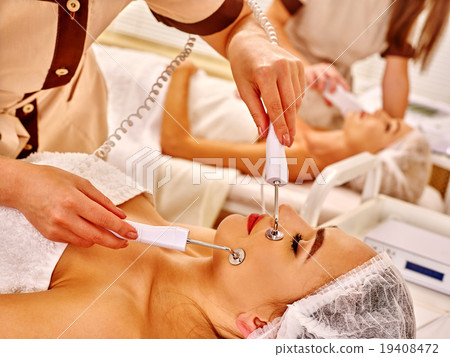 Young woman receiving electric facial massage. 19408472