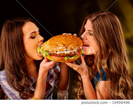 Girls eating big sandwich. 19408496
