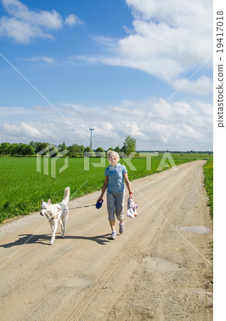 Woman with a dog goes on a country road 19417018
