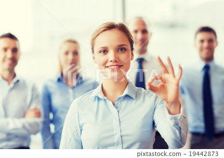 smiling businesswoman showing ok sign in office 19442873