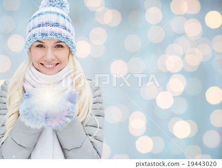 smiling young woman in winter clothes over lights 19443020