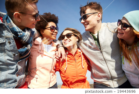 图库照片: smiling friends in sunglasses laughing on street
