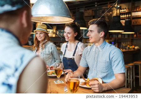 happy friends eating and drinking at bar or pub 19443953