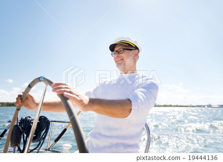 senior man at helm on boat or yacht sailing in sea senior man at helm on boat or yacht sailing in sea 19444136