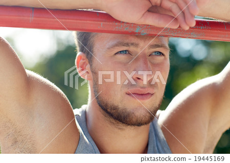 young man exercising on horizontal bar outdoors young man exercising on horizontal bar outdoors 19445169