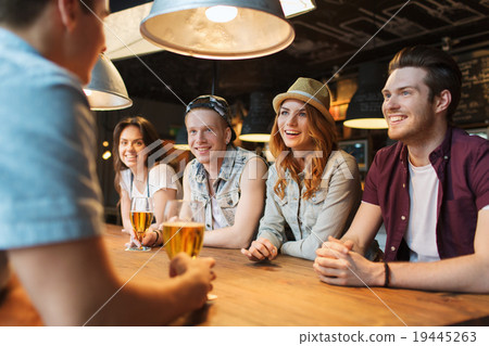 happy friends drinking beer and talking at bar 19445263