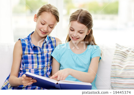 two happy girls reading book at home 19445374