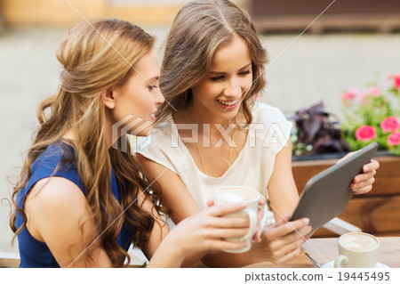 young women with tablet pc and coffee at cafe 19445495