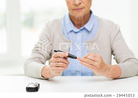 senior woman with glucometer checking blood sugar senior woman with glucometer checking blood sugar 19445853