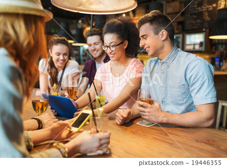 happy friends with tablet pc and drinks at bar 19446355