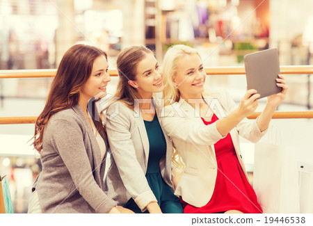 happy young women with tablet pc and shopping bags happy young women with tablet pc and shopping bags 19446538
