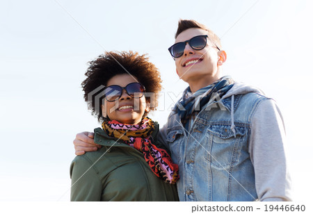 happy teenage friends in shades hugging outdoors happy teenage friends in shades hugging outdoors 19446640