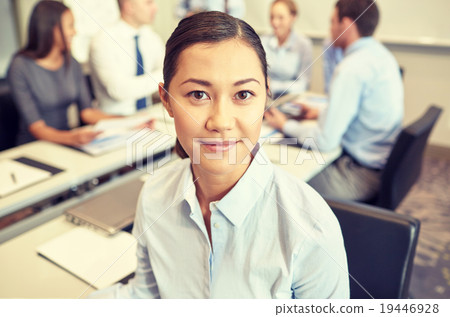 group of smiling businesspeople meeting in office 19446928