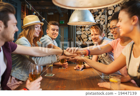 happy friends with drinks and hands on top at bar 19447139
