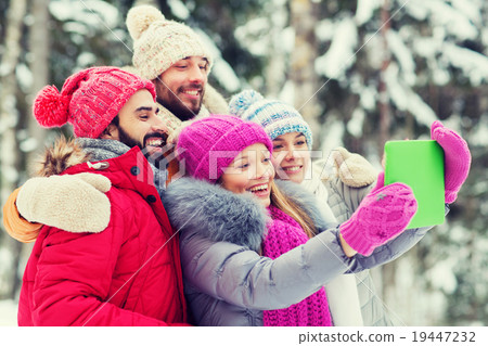 smiling friends with tablet pc in winter forest 19447232