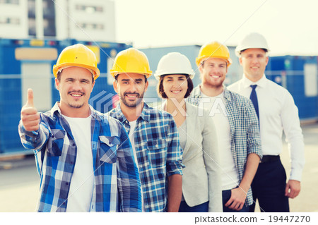 group of smiling builders in hardhats outdoors group of smiling builders in hardhats outdoors 19447270
