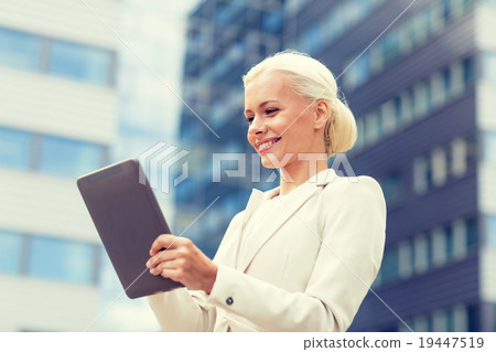 smiling businesswoman with tablet pc outdoors 19447519
