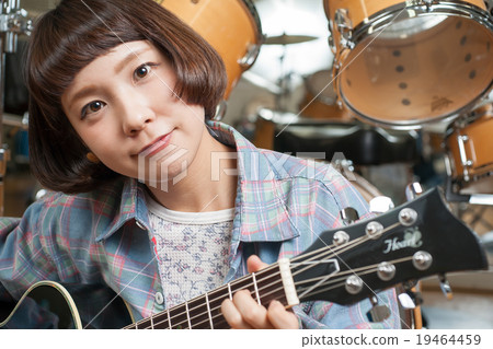 A girl playing an acoustic guitar A girl playing an acoustic guitar 19464459