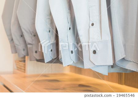 shirts hanging on rack in wooden wardrobe 19465546