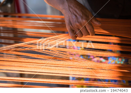orange silk thread in sewing or weaving machine 19474043