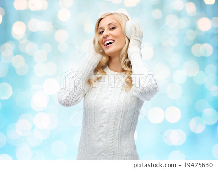 smiling young woman in winter earmuffs and sweater 19475630